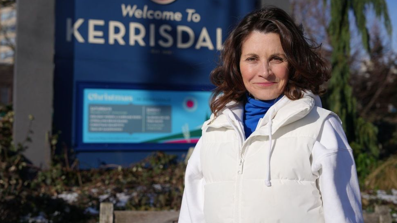 Dallas Brodie, standing in front of Kerrisdale sign.