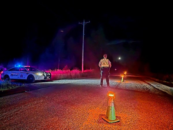 A BC Highway Patrol officer waits at a check stop in the Kootenays with a patrol car at roadside