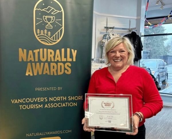 Karen of Escape Travel Wear holding a Naturally Awards certificate at the North Vancouver boutique